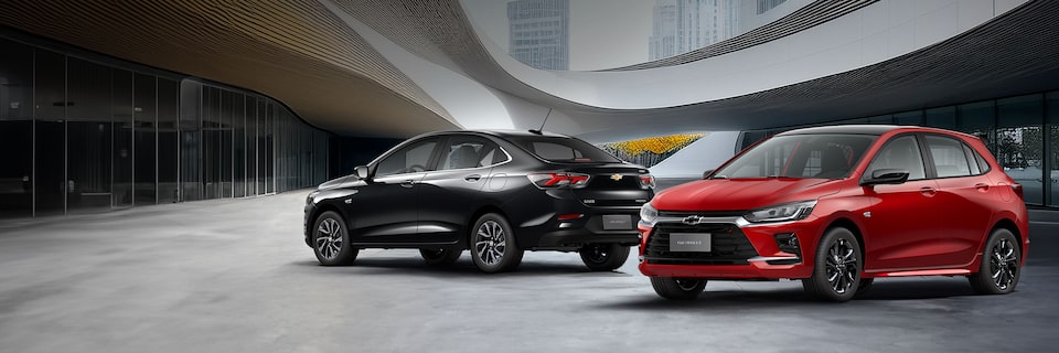 Chevrolet Onix 2026 color Rojo Jinx y Onix Plus 2026 color Negro Black Meet Kettle estacionados en área urbana